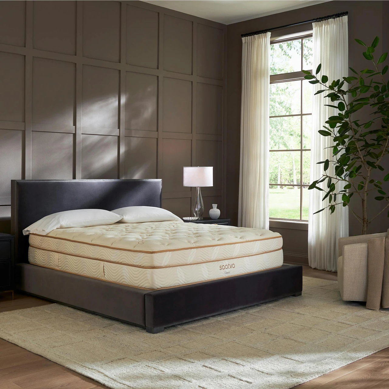 Saatva Classic mattress in a styled bedroom with a dark upholstered bed