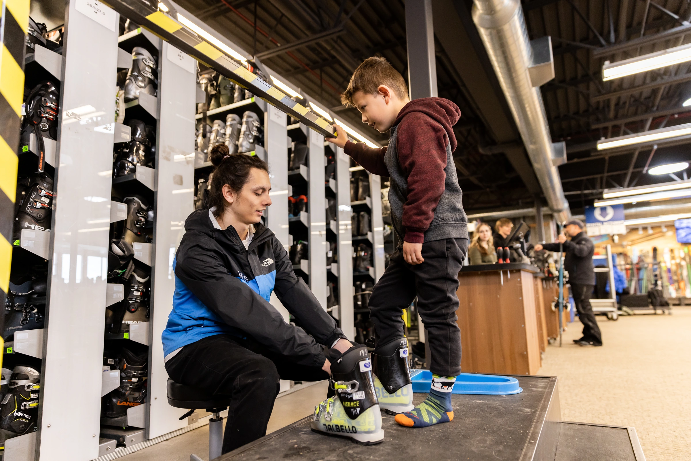 Christy Sports team member helping a young customer with ski boot fitting