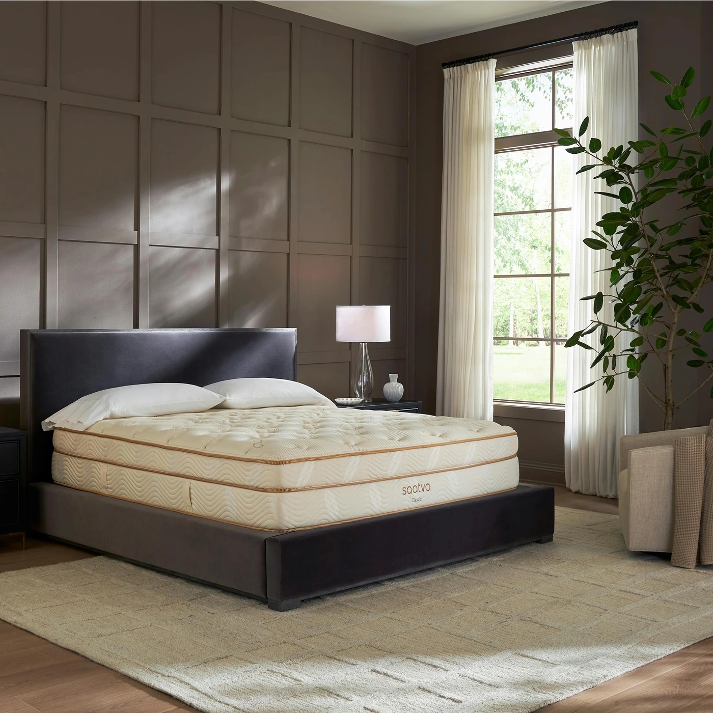 Saatva Classic mattress in a styled bedroom with a dark upholstered bed