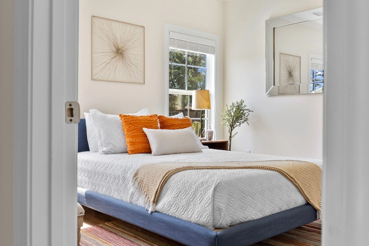 Bright vacation rental bedroom with a blue bed frame and warm-toned pillows