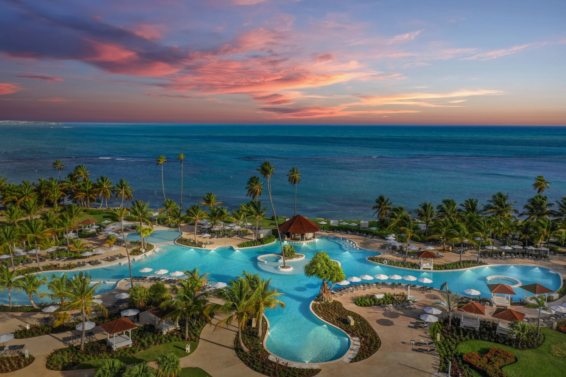 Hyatt Regency Grand Reserve resort pool and palm-lined beach overlooking the ocean at sunset