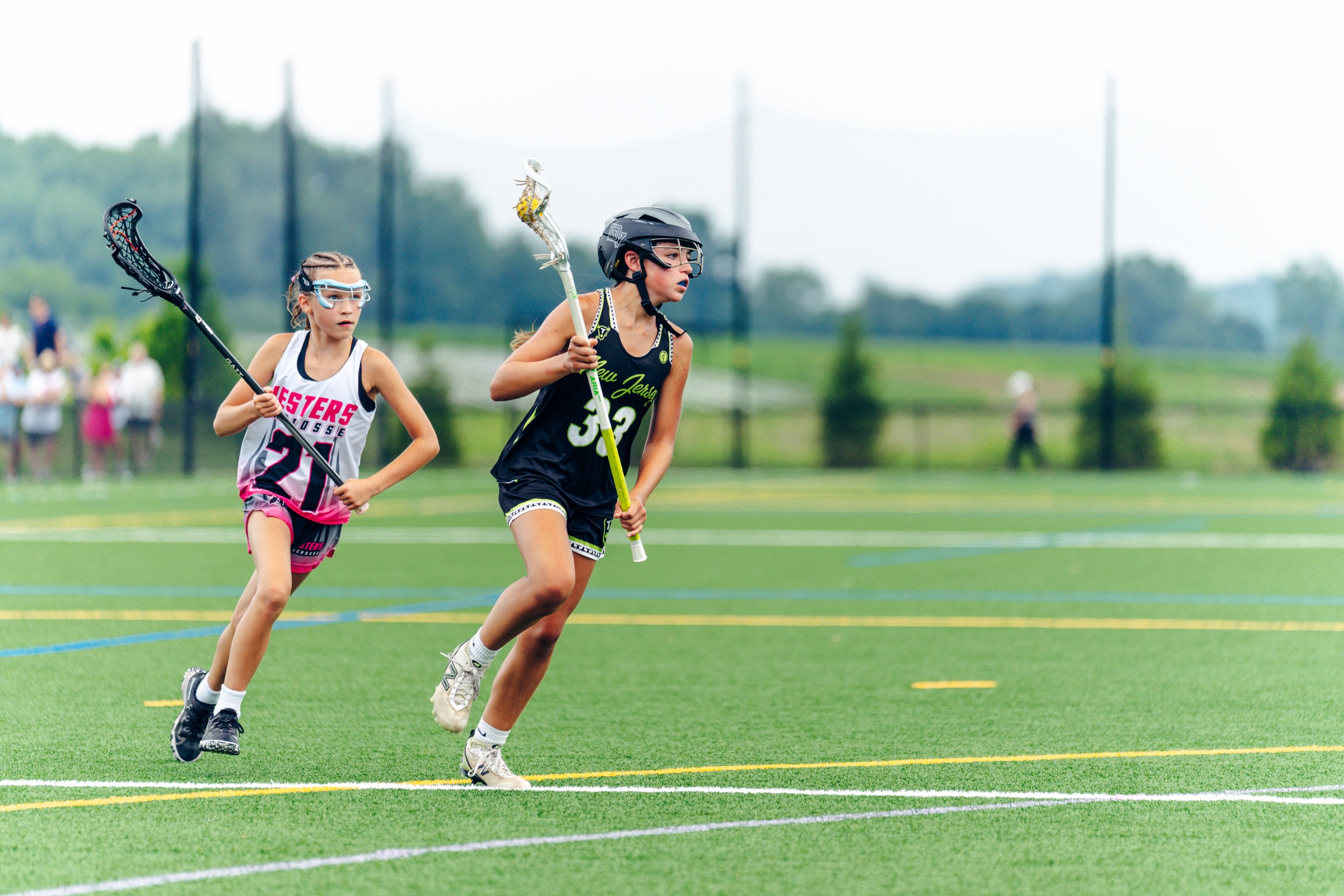 Two girls competing in a lacrosse game