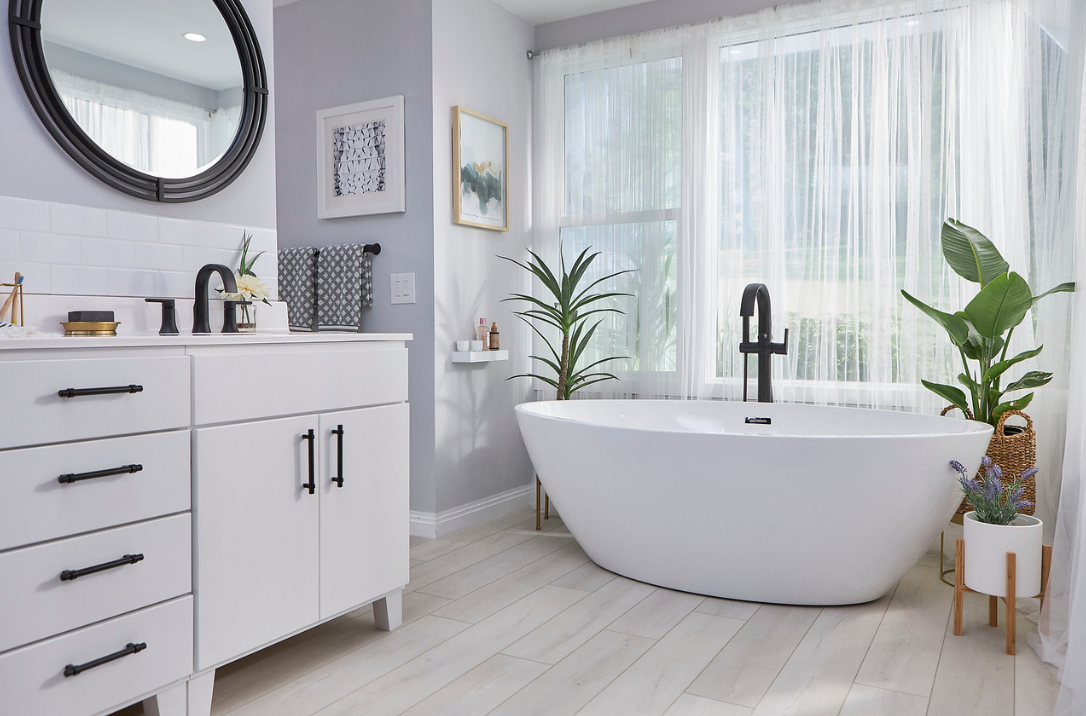 Re-Bath bathroom with a freestanding tub, white vanity and black fixtures